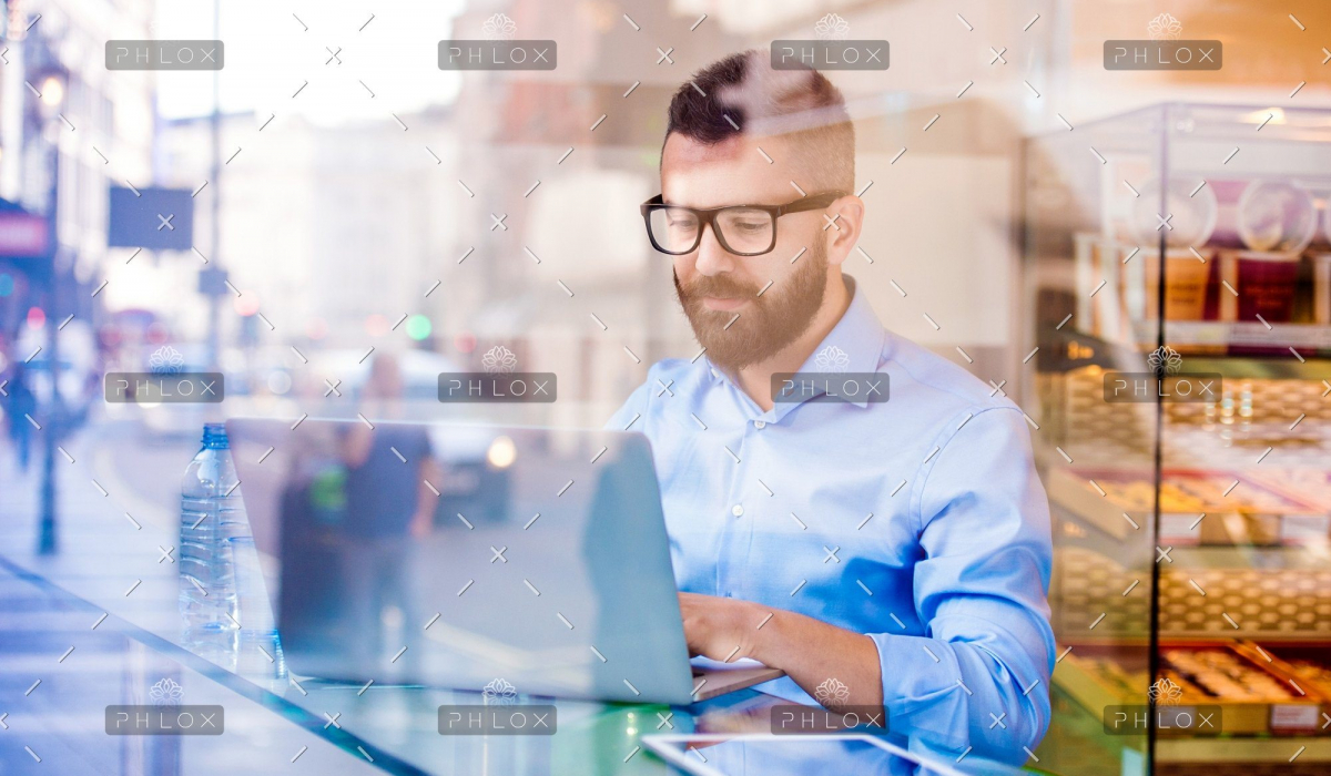 demo-attachment-146-Hipster-manager-in-cafe-working-on-laptop-by-window